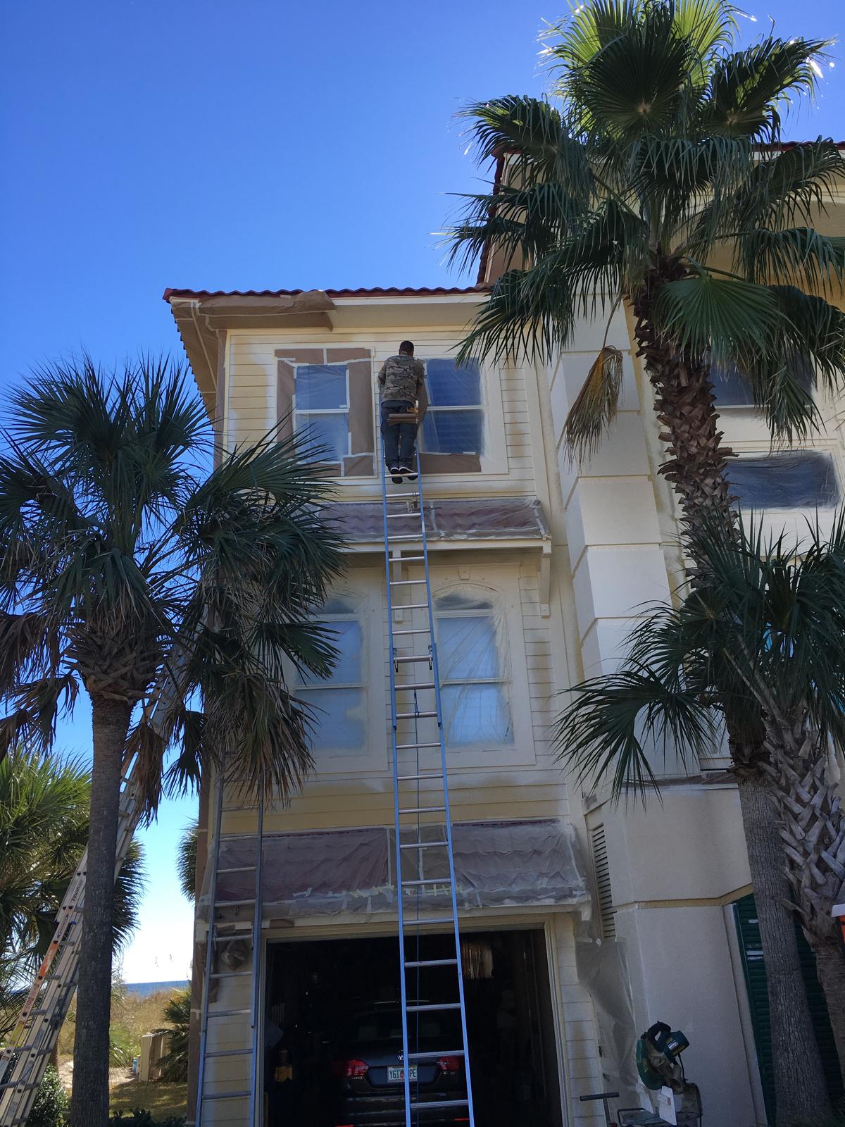 Exterior repaint of a three-story Florida home surrounded by palms